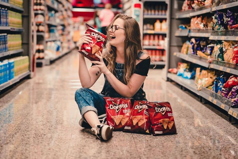 smiling woman holding pack of Doritos and wondering "Can Hamsters Eat doritos?"