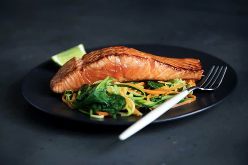 cooked salmon on a plate with veggies leads to questions like "can hamsters eat salmon?"