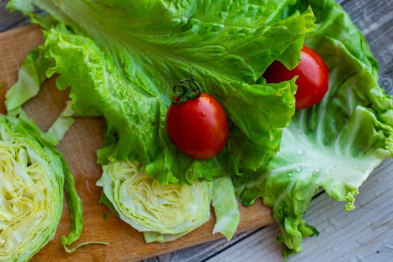 fresh watered lettuce with other veggies on a wooden board