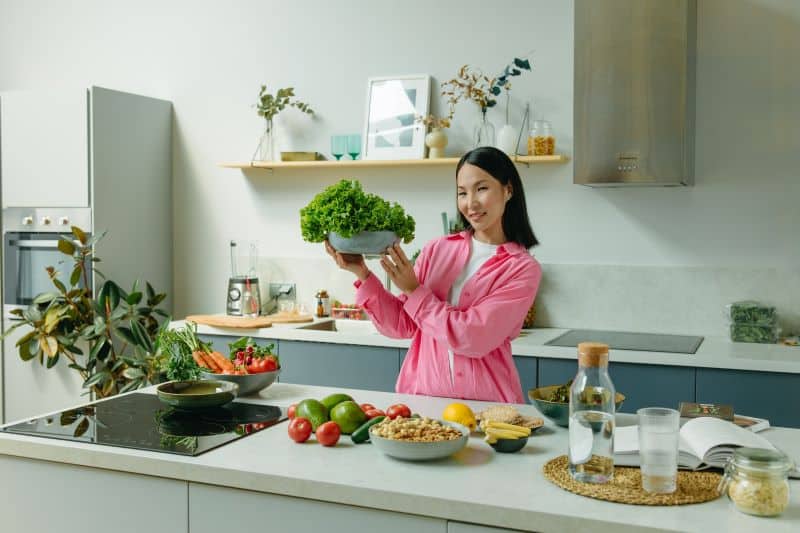 woman holding a large bowl of lettuce in the kitchen