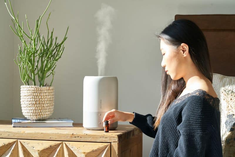 Asian woman with essential oil and humidifier in the background