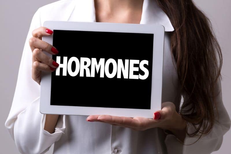 woman holding a board with "hormones" inscribed