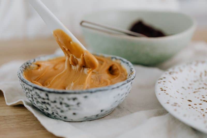 peanut butter in a white bowl with plastic spatula